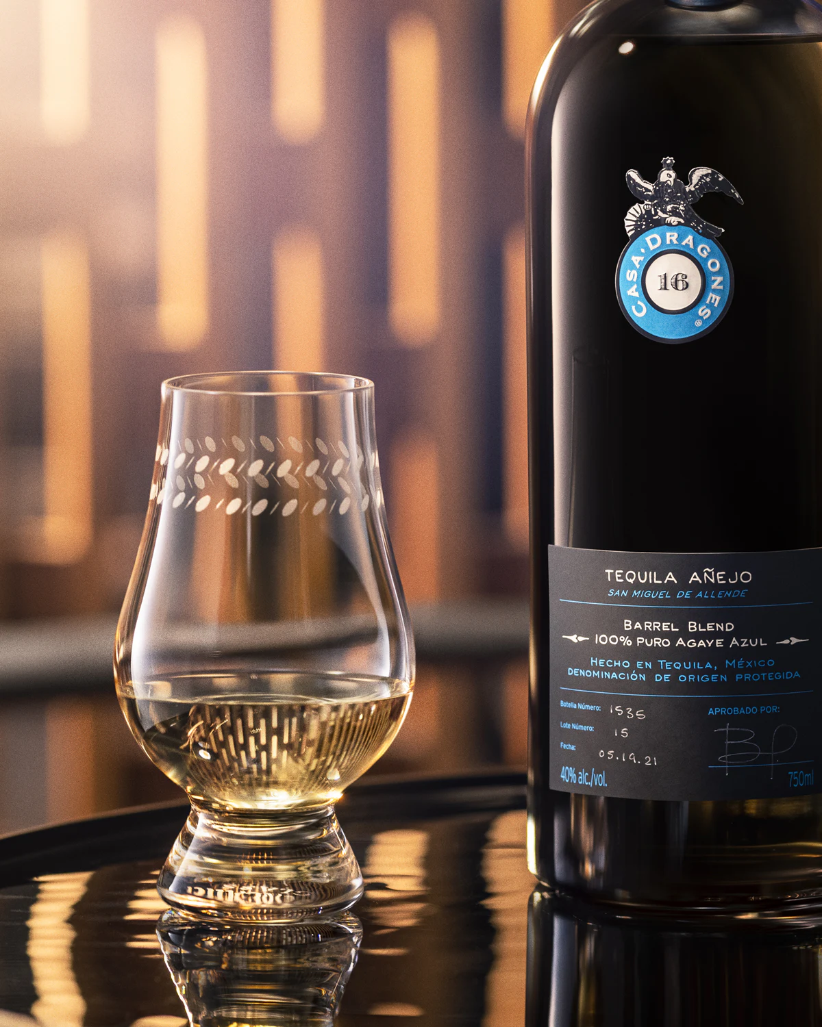 Copa y botella de Casa Dragones Añejo bajo luz cálida